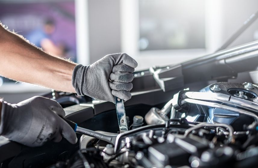 Behandschuhte Hände bei Wartungsarbeiten im Motorraum