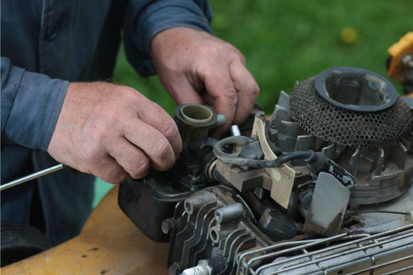 Wartungsarbeiten am Benzinmotor eines Rasenmähers